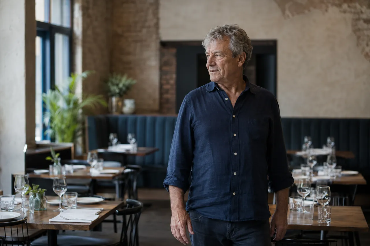 A restaurant owner standing among set tables in his dining room before service