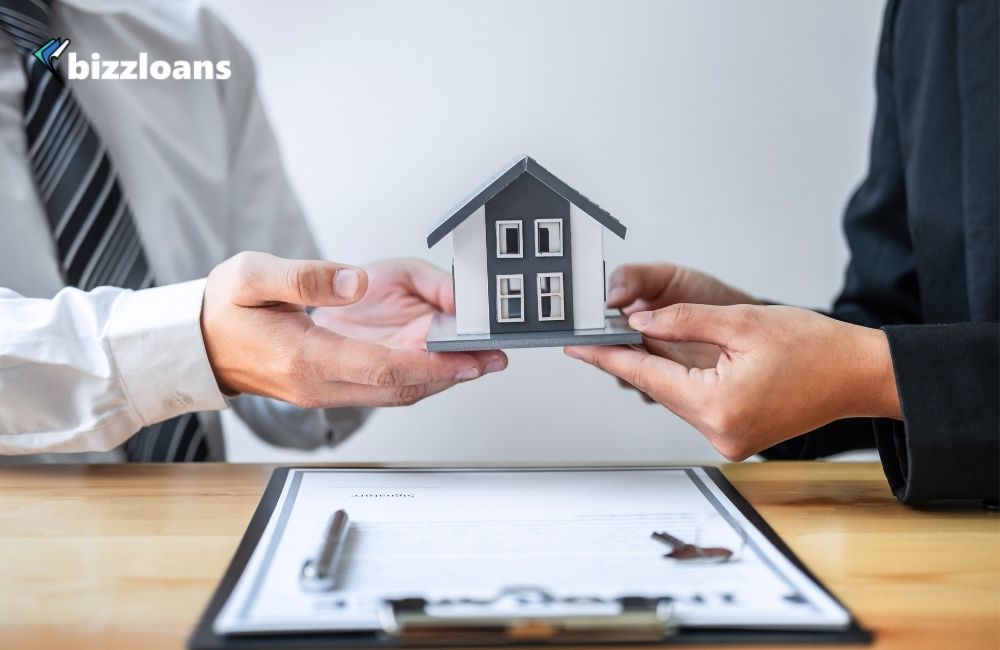 Two hands of business owners holding a Miniature of House