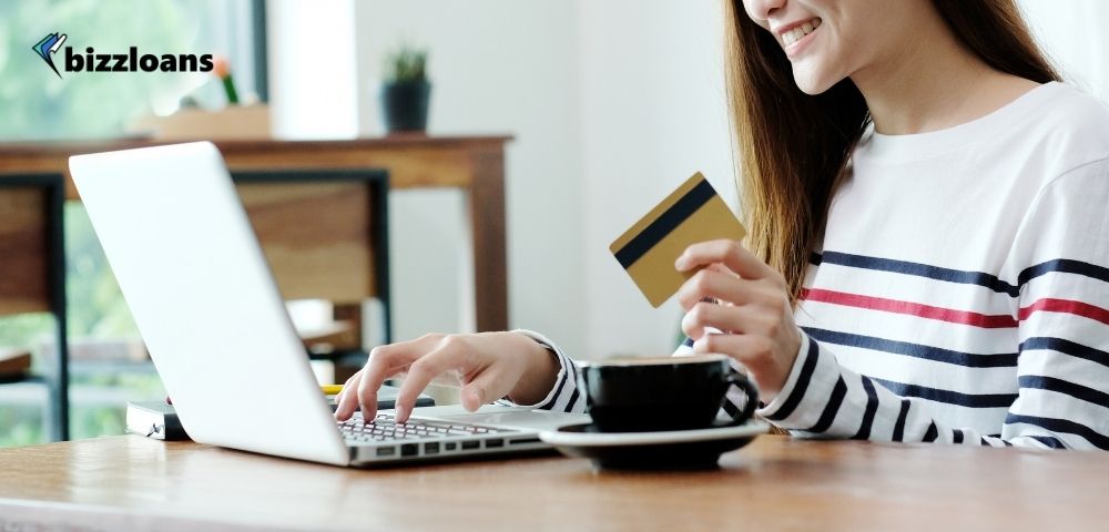 Young asian woman holding a business credit card while using her laptop at home