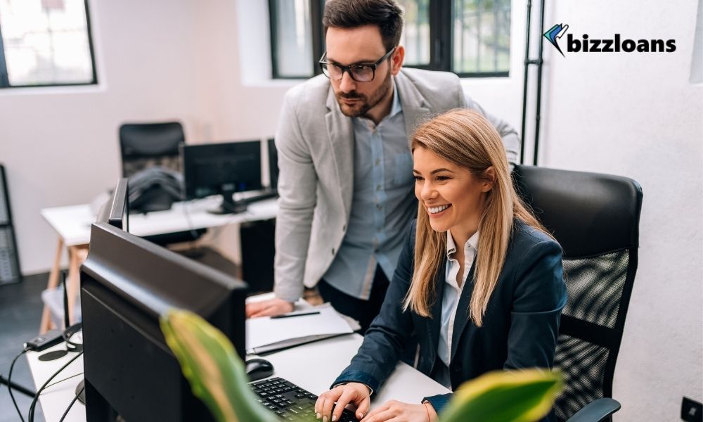 Male business owner delegating work to a female staff while working on a computer