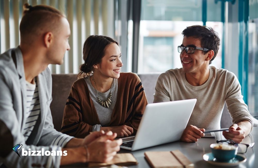 3 business owners talking to each other about b2b platforms while using a laptop