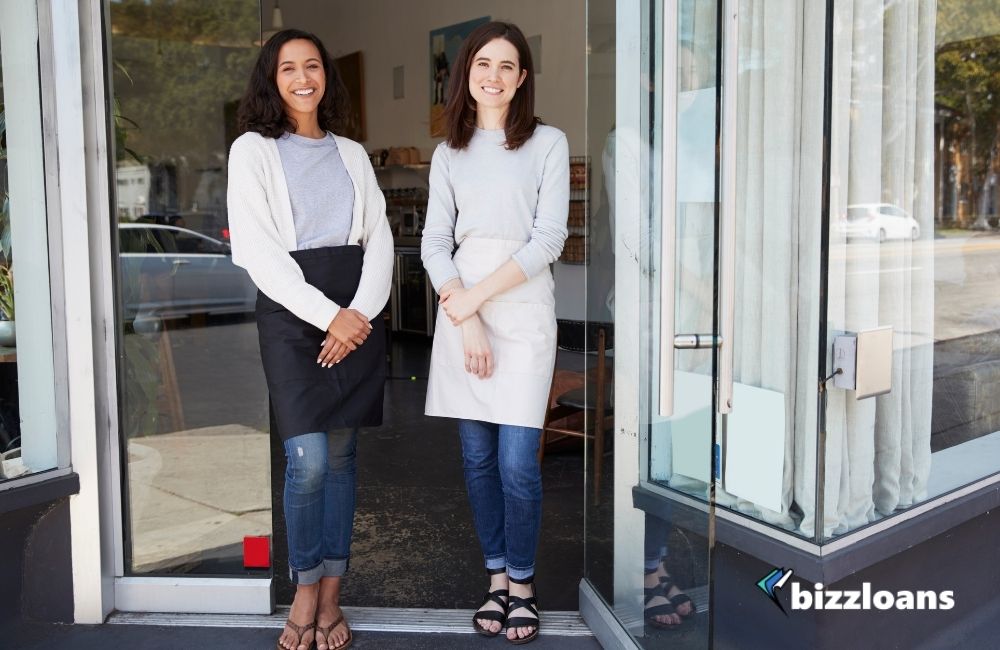 two happy employees standing in front of their shop