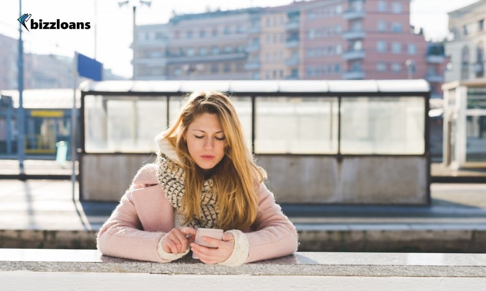 business owner standing near a train station using smartphone while doing sms marketing