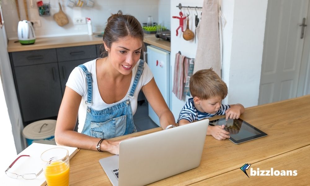 small business owner working from home on her laptop with her kid on the side 