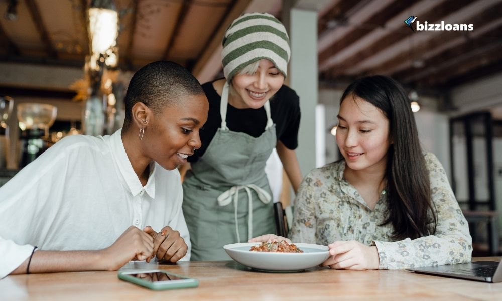 happy customers and waiter looking at a food on the table