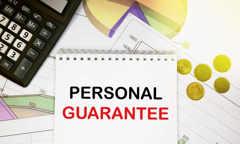 Personal guarantee on notepad with calculator, coins, graphics on financial report.
