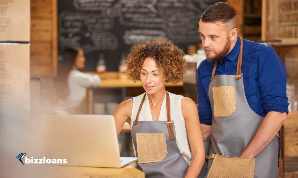 two business owners in the restaurant searching for equipment financing on laptop